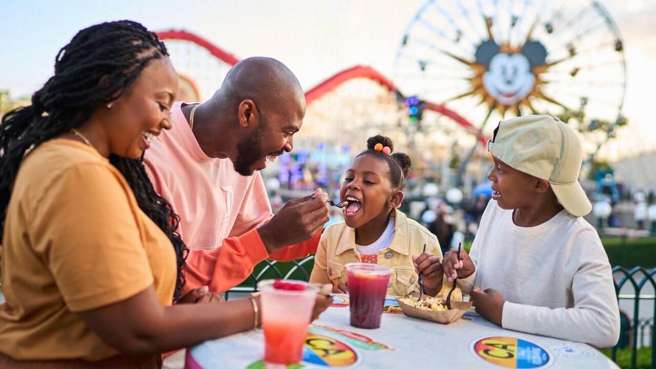 A family of 4 enjoying snacks and beverages in Paradise Gardens Park at Disney California Adventure Park