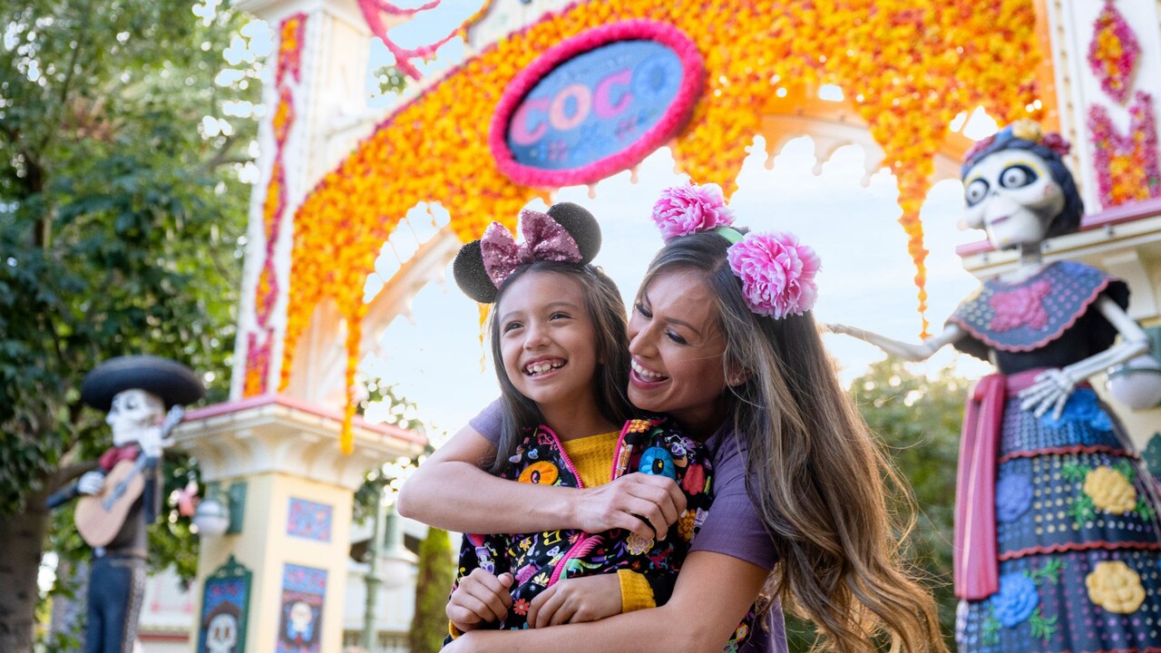A mother and young daughter embracing in front of the Plaza de la Familia at Disney California Adventure Park