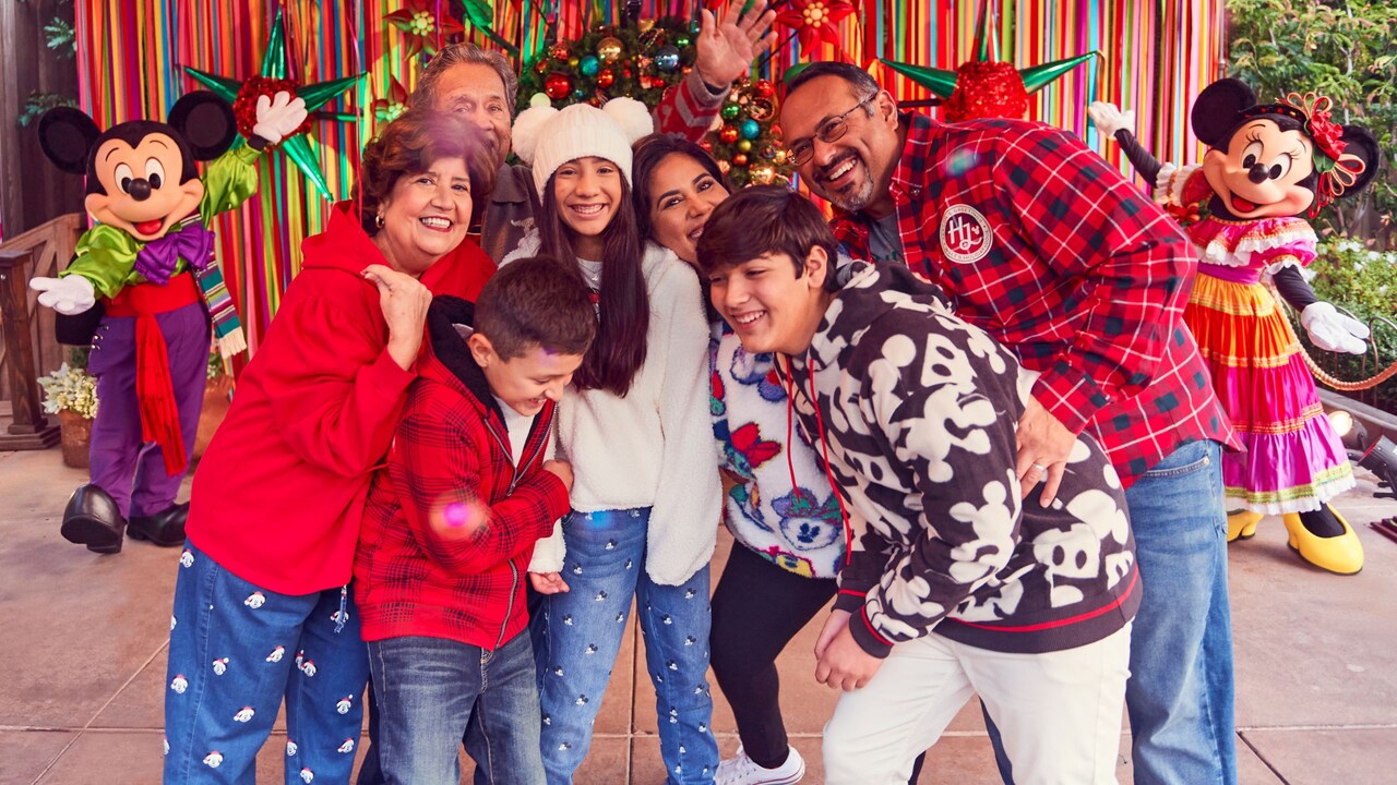 A family posing with Mickey Mouse and Minnie Mouse at Disney Viva Navidad	