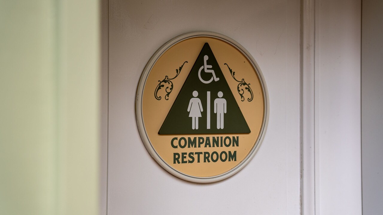 Un letrero de baño con acompañante