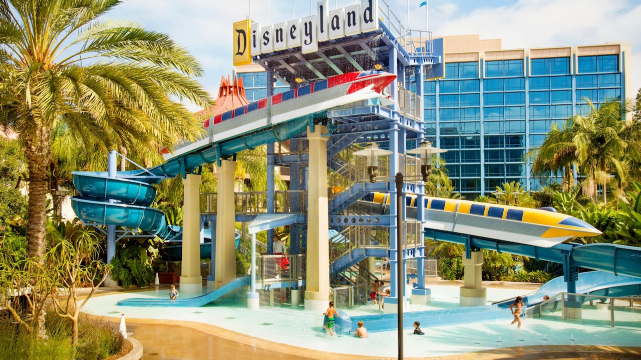 An outdoor pool and monorail themed water slide with signage that reads Disneyland