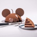 A milk chocolate flavored Mickey Mouse Celebration Cake next to a slice of the same cake