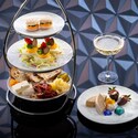 Plates of charcuterie, deviled eggs, macarons, pastries and chocolate dipped strawberries next to 2 glasses of champagne against a backdrop of Spaceship Earth