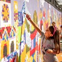 A girl in Disney themed apparel painting on a mural with geometric shapes