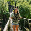A girl wearing Mickey ears and a vest stands on a rope bridge at Disney's Animal Kingdom theme park