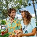 A man and a woman carrying a plate of food and a drink at EPCOT