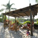 A family of 6 seated in Adirondack chairs under a wooden gazebo like structure surrounded by palm trees at Disney’s Typhoon Lagoon water park