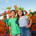 A young boy and girl smiling for a photo together in Toy Story Land near the Slinky Dog Dash coaster