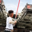 A young boy holding a lightsaber near the Millennium Falcon in Star Wars Galaxy's Edge