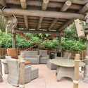 A covered outdoor lounge featuring a television screen, chairs and table at Disney’s Typhoon Lagoon water park