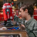 A young boy examining an assembled droid resting on a workbench at Droid Depot  