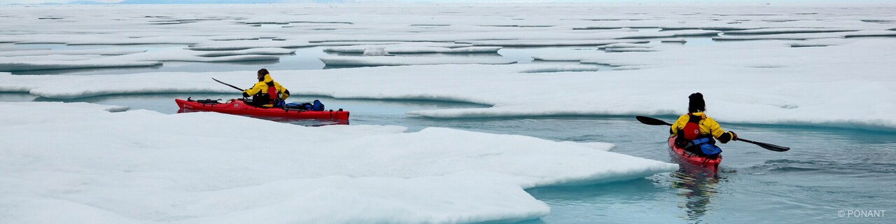 Two kayakers navigate ice floes in the Southern ocean