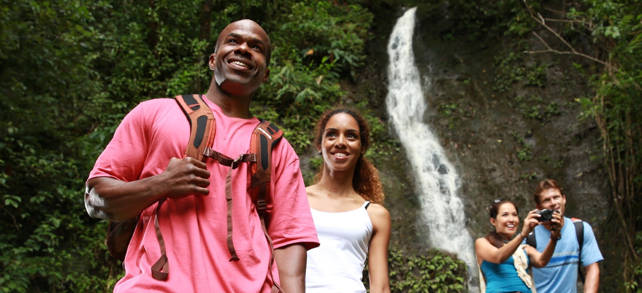 Two couples on an Aulani hiking excursion visit a waterfall