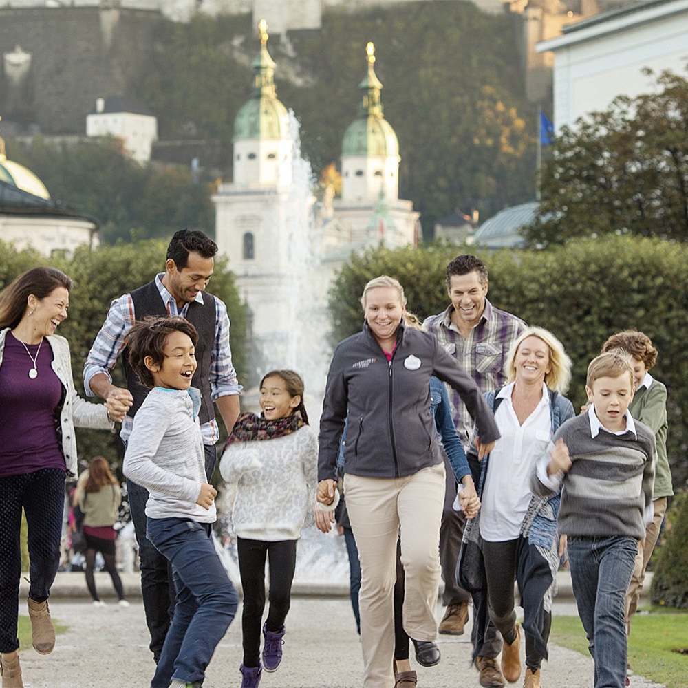 2 families happily stroll down a path by a fountain near historic buildings 2 families happily stroll down a path by a fountain near historic buildings