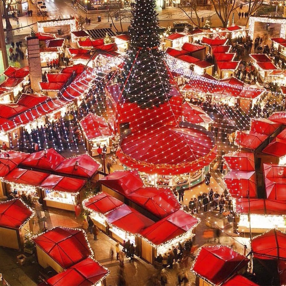 Tented roofs of shops surround a Christmas tree outside a hotel at a Christmas Market Tented roofs of shops surround a Christmas tree outside a hotel at a Christmas Market