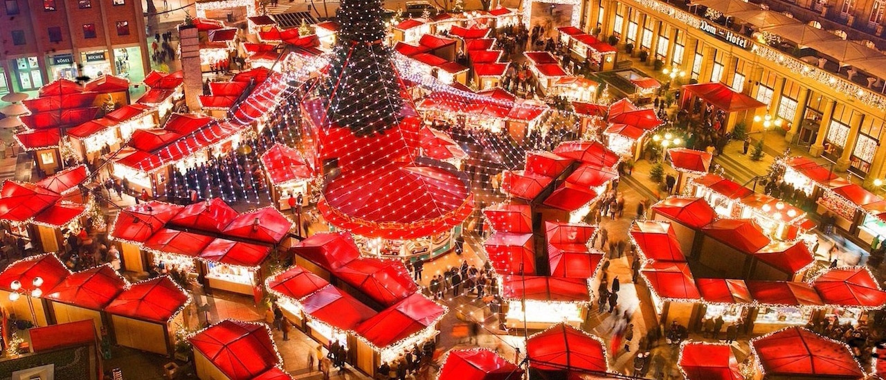 Tented roofs of shops surround a Christmas tree outside a hotel at a Christmas Market Tented roofs of shops surround a Christmas tree outside a hotel at a Christmas Market