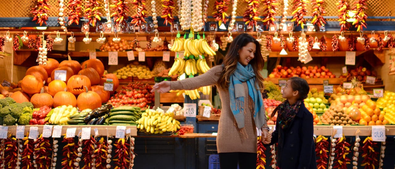 A mother and daughter shop in an outdoor store with fresh fruits and vegetables A mother and daughter shop in an outdoor store with fresh fruits and vegetables