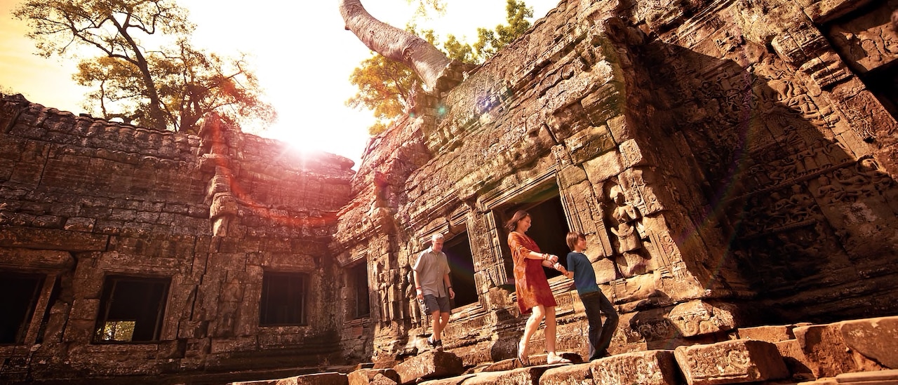A boy holds his mother's hand with his father following as they explore an ancient temple