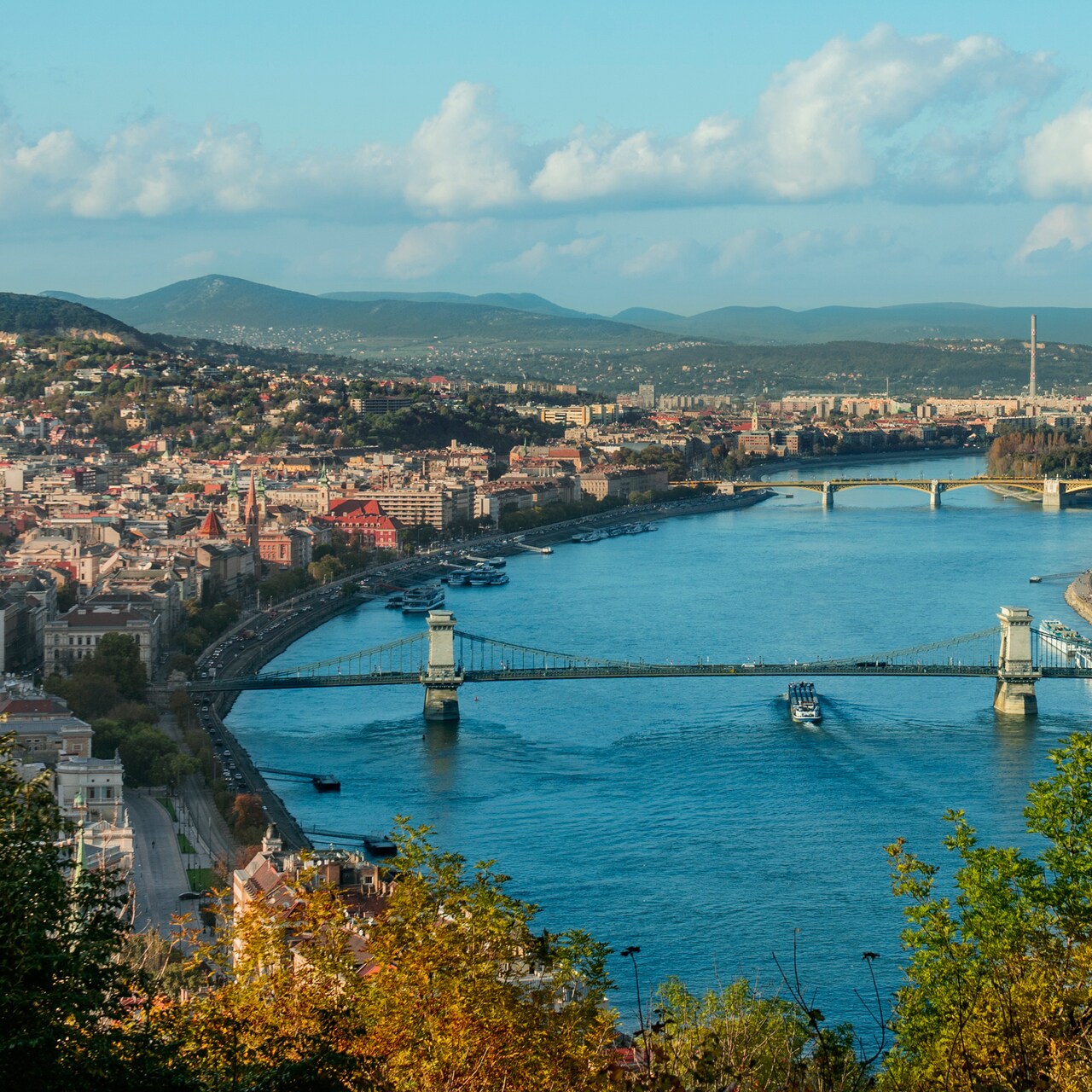 The Danube River with 2 bridges and city buildings on both shores The Danube River with 2 bridges and city buildings on both shores