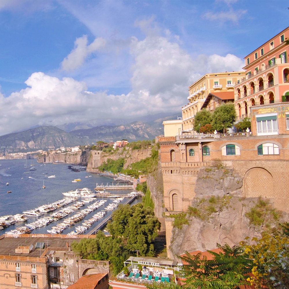 Buildings with arched balconies along the coast where boats line docks Buildings with arched balconies along the coast where boats line docks