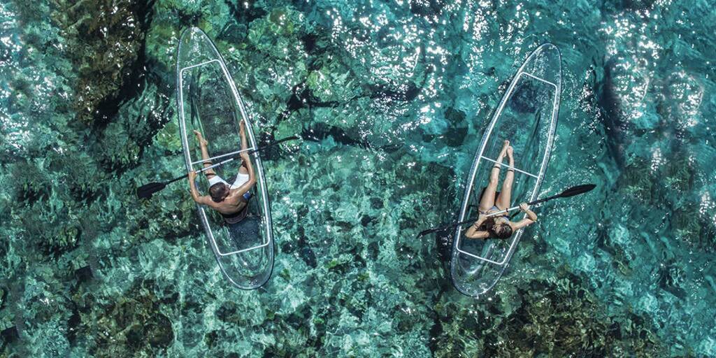 Two people kayaking in glass bottom kayaks on ocean water