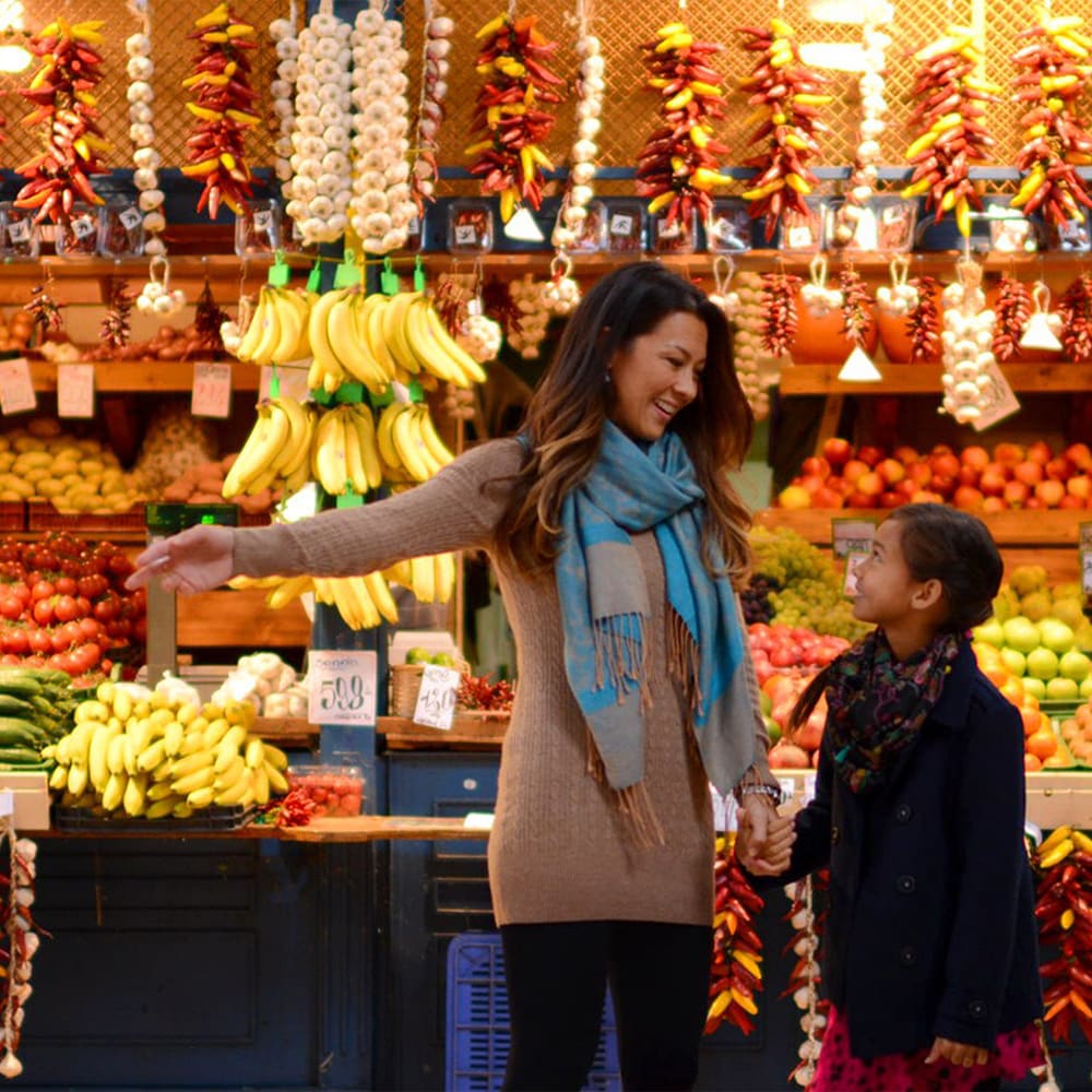 A mother and daughter shop in an outdoor store with fresh fruits and vegetables A mother and daughter shop in an outdoor store with fresh fruits and vegetables