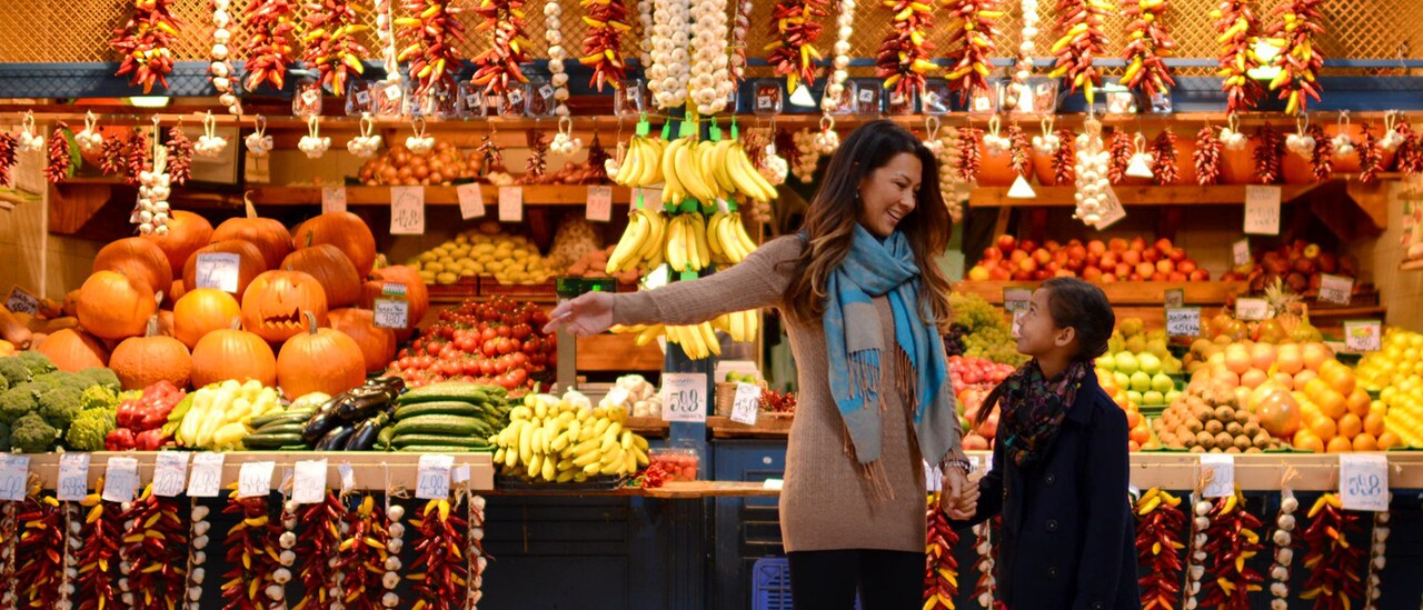 A mother and daughter shop in an outdoor store with fresh fruits and vegetables A mother and daughter shop in an outdoor store with fresh fruits and vegetables