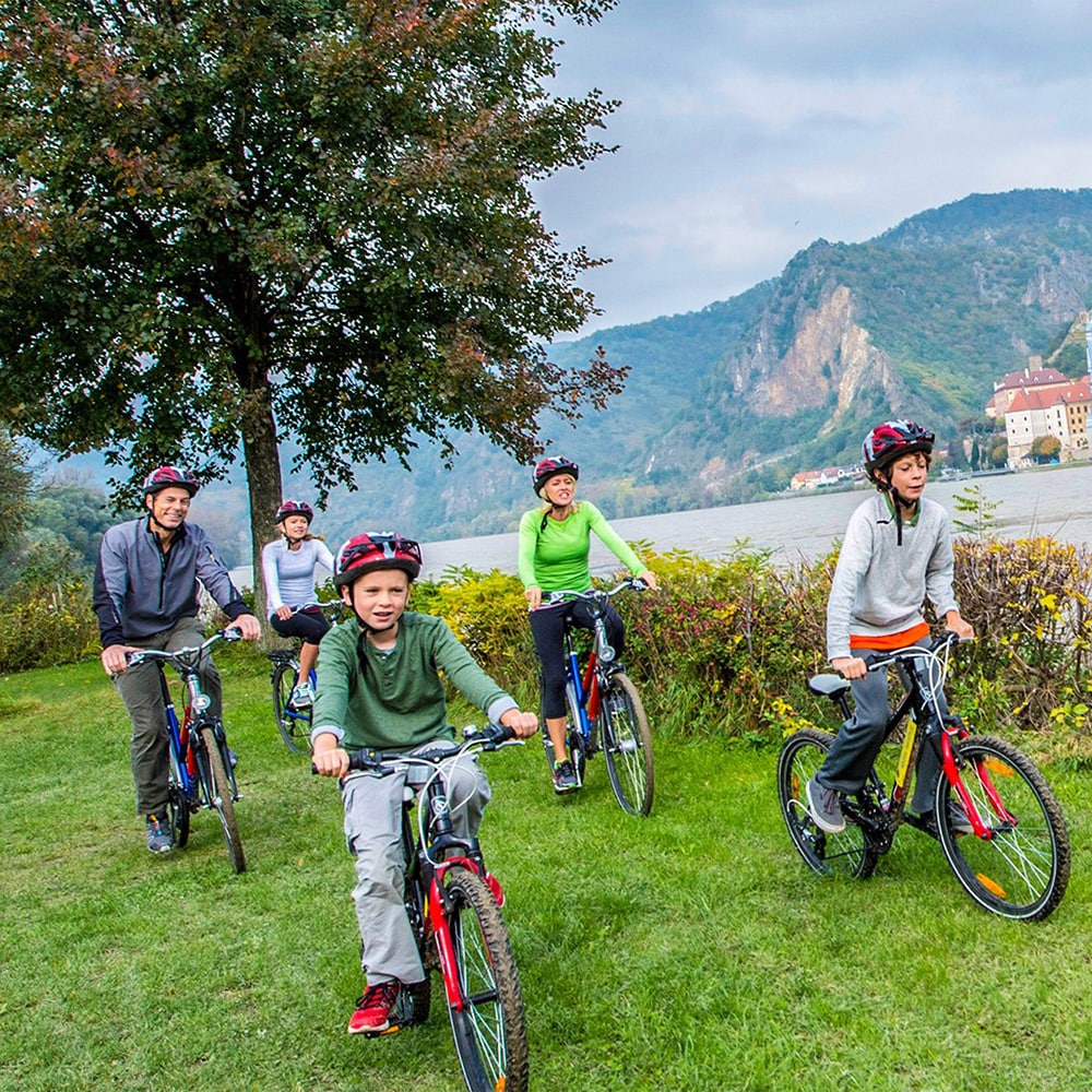 An Adventure guide leads a family biking along the shore of the Danube River An Adventure guide leads a family biking along the shore of the Danube River