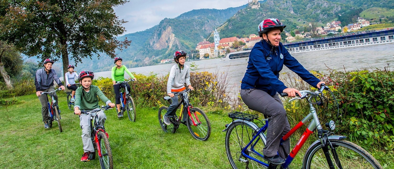 An Adventure guide leads a family biking along the shore of the Danube River An Adventure guide leads a family biking along the shore of the Danube River