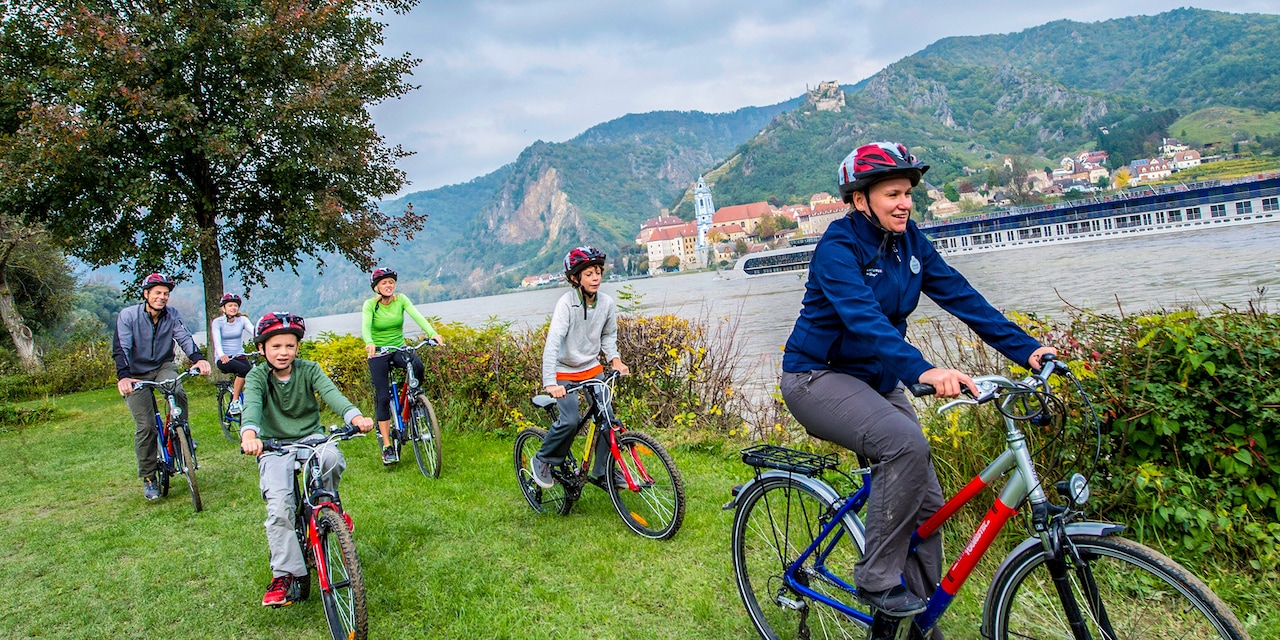 An Adventure guide leads a family biking along the shore of the Danube River An Adventure guide leads a family biking along the shore of the Danube River