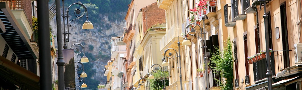 A row of buildings along a street lamp-lined avenue in Salerno, Italy lead to a verdant mountainside A row of buildings along a street lamp-lined avenue in Salerno, Italy lead to a verdant mountainside