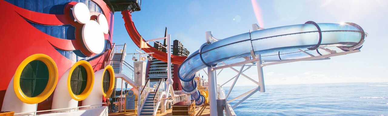 The top deck of the Disney Magic cruise ship with the AquaDunk water slide extending over the ocean and the Mickey Mouse logo on the ship’s Forward Funnel The top deck of the Disney Magic cruise ship with the AquaDunk water slide extending over the ocean and the Mickey Mouse logo on the ship’s Forward Funnel