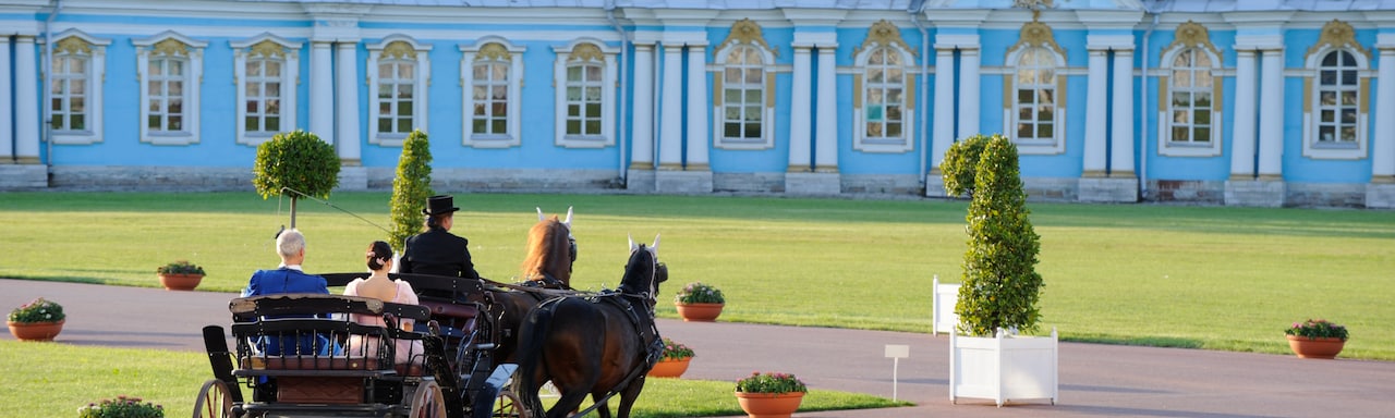 A buggy driver takes a couple on a horse and buggy ride at the grounds of a palace A buggy driver takes a couple on a horse and buggy ride at the grounds of a palace