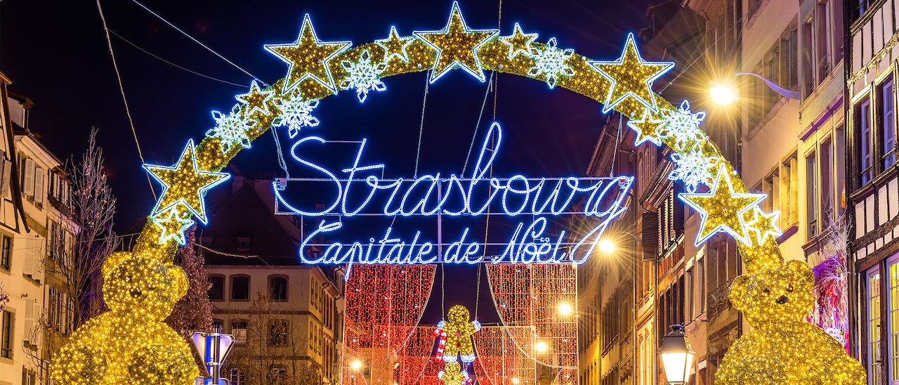 A lit-up sign between two buildings says Strasbourg Capitale de Noel