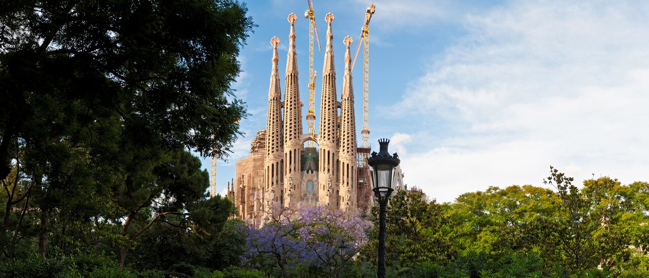 The whimsical spires of Gaudí's Sagrada Família in Barcelona loom above the treetops
