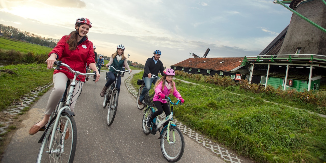 An Adventure Guide riding bikes with a socially distant group on a path with windmills