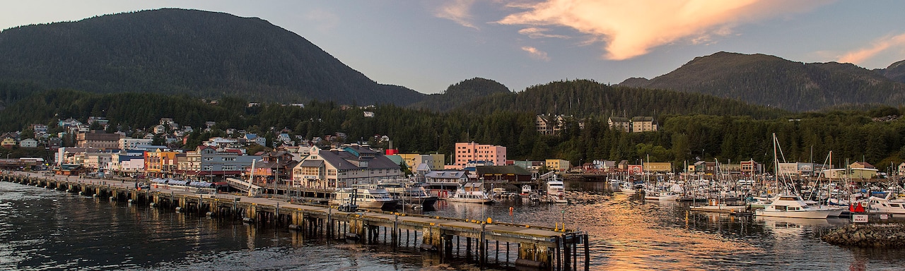 A pier juts out into the water near a small Alaskan seafront town A pier juts out into the water near a small Alaskan seafront town