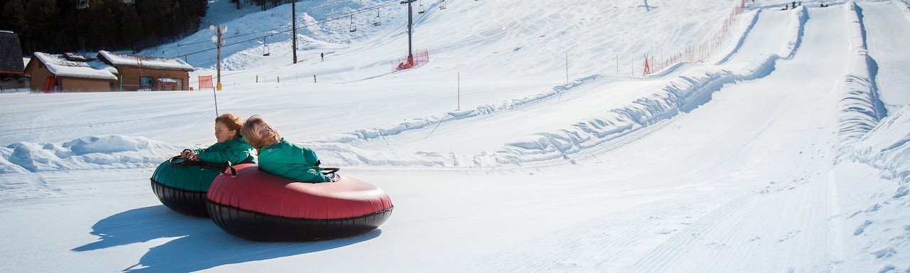 Two girls ride inner-tubes down a snowy track at Snow King Mountain in Jackson, Wyoming Two girls ride inner-tubes down a snowy track at Snow King Mountain in Jackson, Wyoming