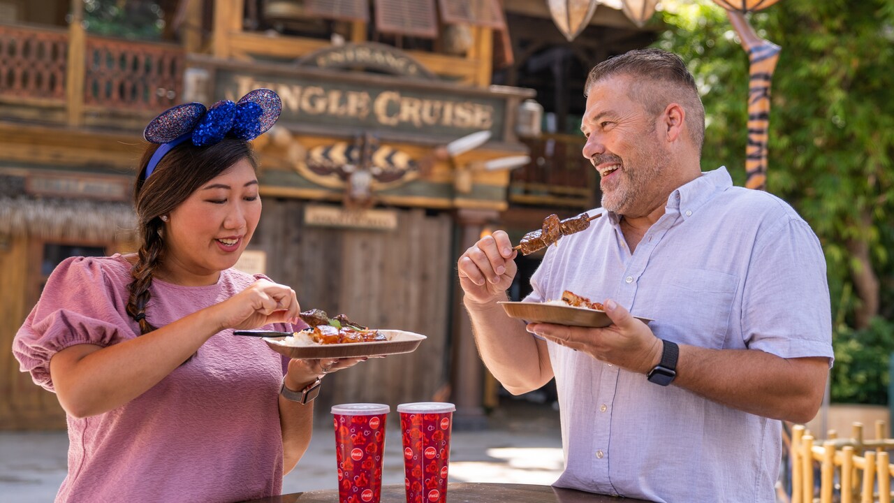 Un hombre y una mujer disfrutando de pequeños bocadillos afuera de Jungle Cruise