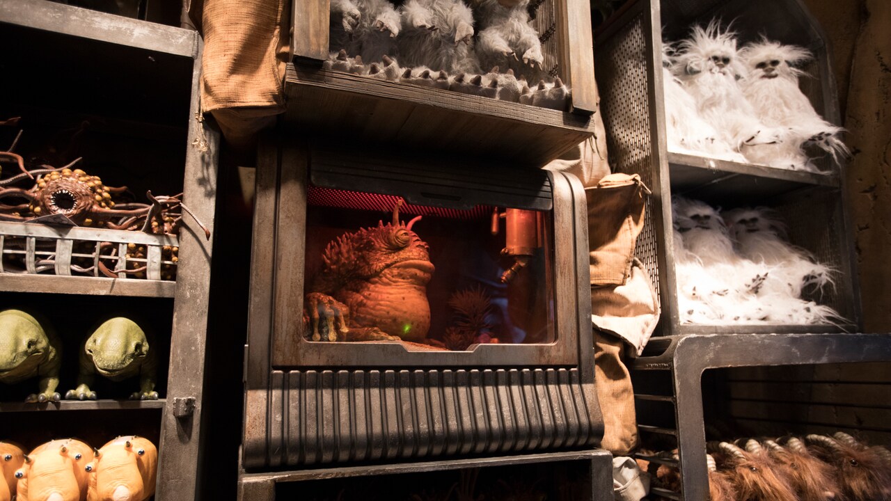 A worrt sits in a crate surrounded by other creatures, including plush banthas, puffer pigs, dewbacks and rathtars.