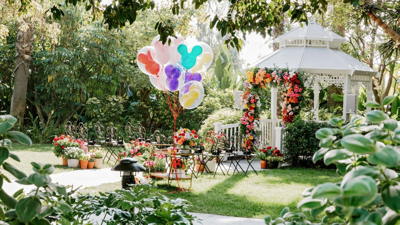Un lugar para celebrar bodas con jardín, glorieta, arco floral, arreglos florales, sillas y globos de Mickey Mouse