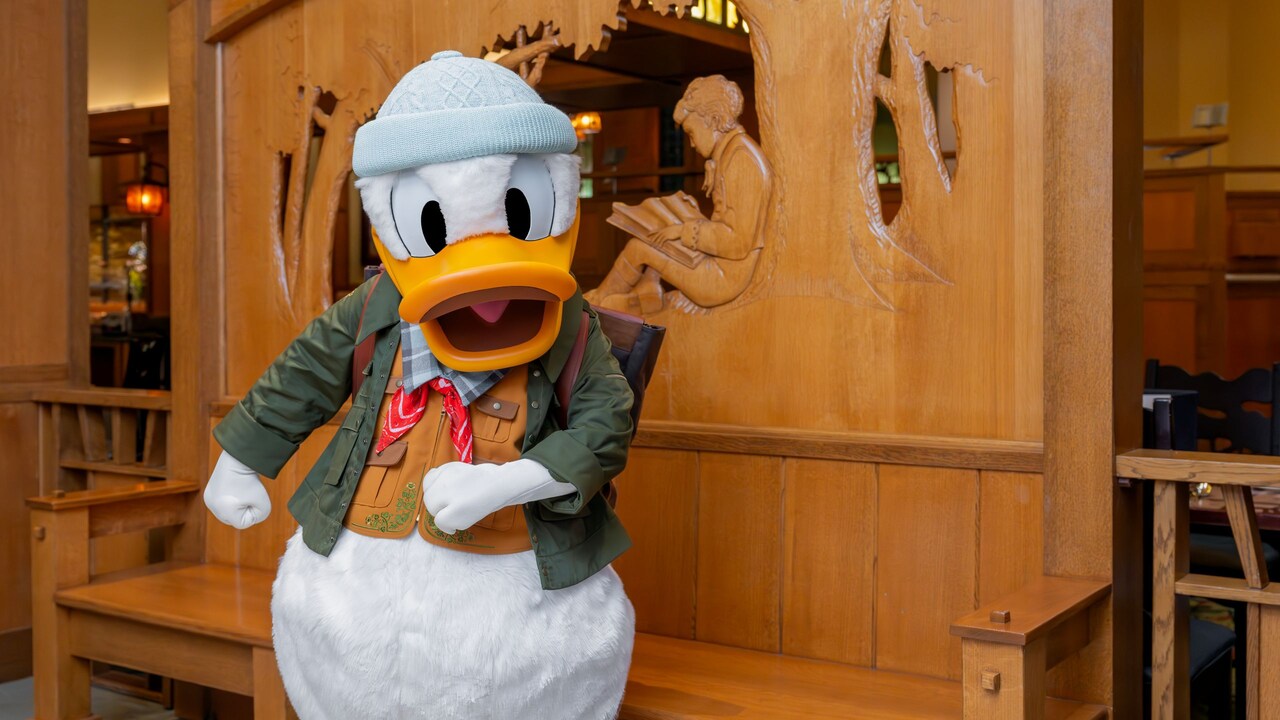 Donald Duck vestido con un atuendo para salir al aire libre cerca de un detallado banco de madera en Disney's Grand Californian Hotel & Spa