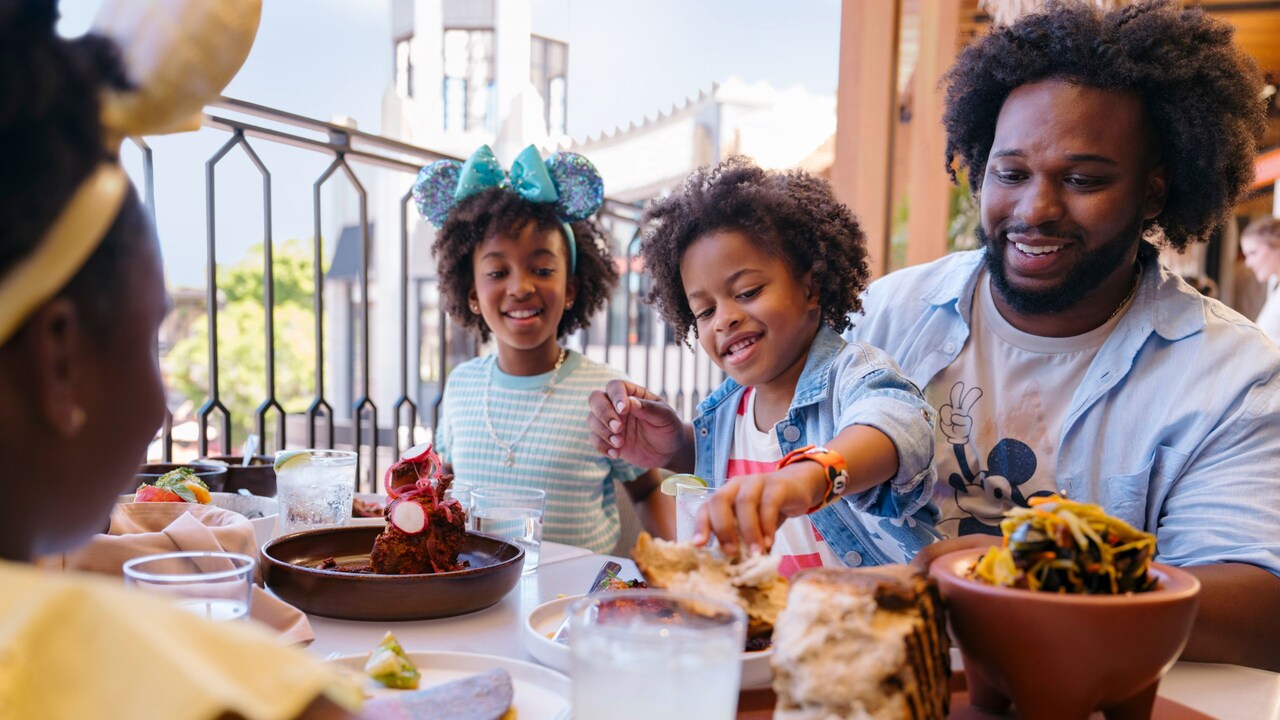 A family of 4 dining at a table in Paseo with a view of Disney Downtown District