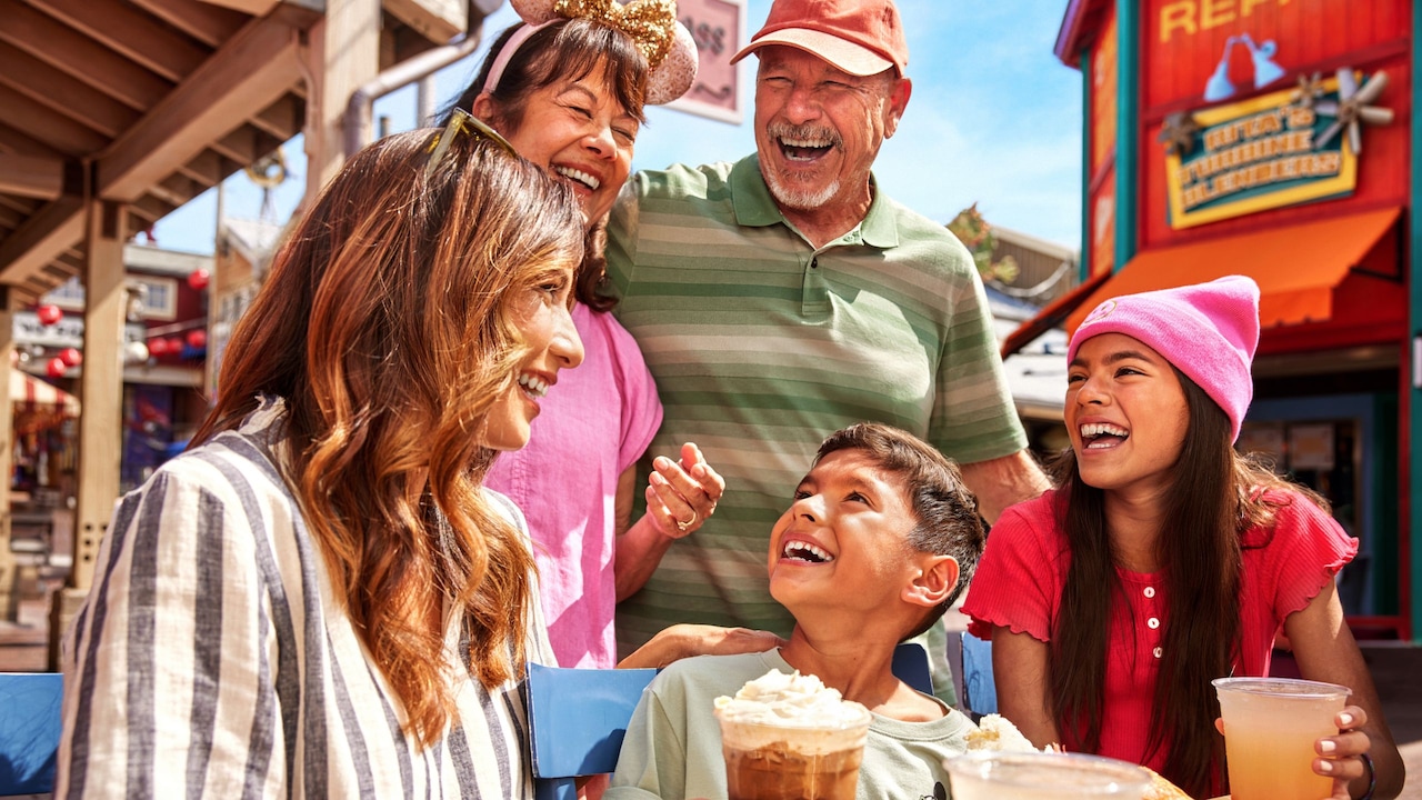 Una familia de 6 personas disfrutando de bebidas y riendo en Paradise Gardens Park en Disneyland Resort