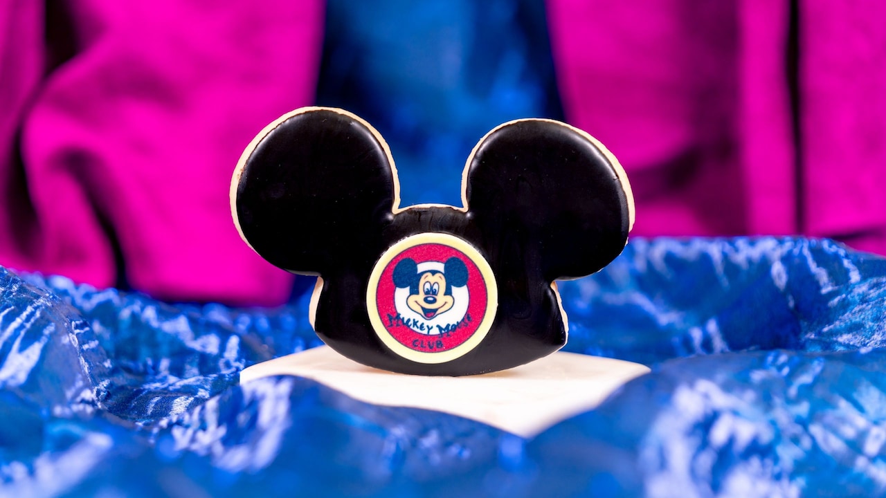 A cookie shaped like a Mickey Mouse ear hat featuring a Mickey Mouse Club logo