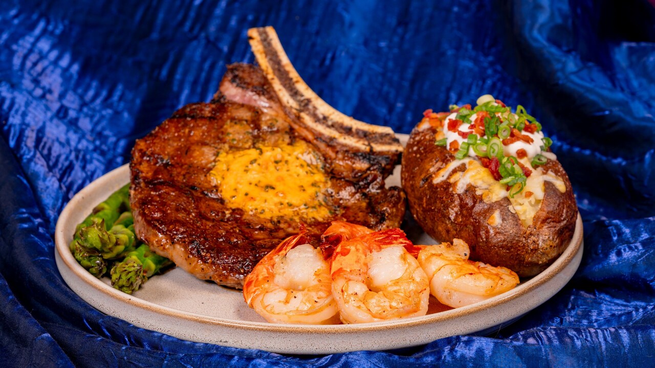 Un corte de res ribeye y camarones con mantequilla occidental, papa rellena asada y espárragos