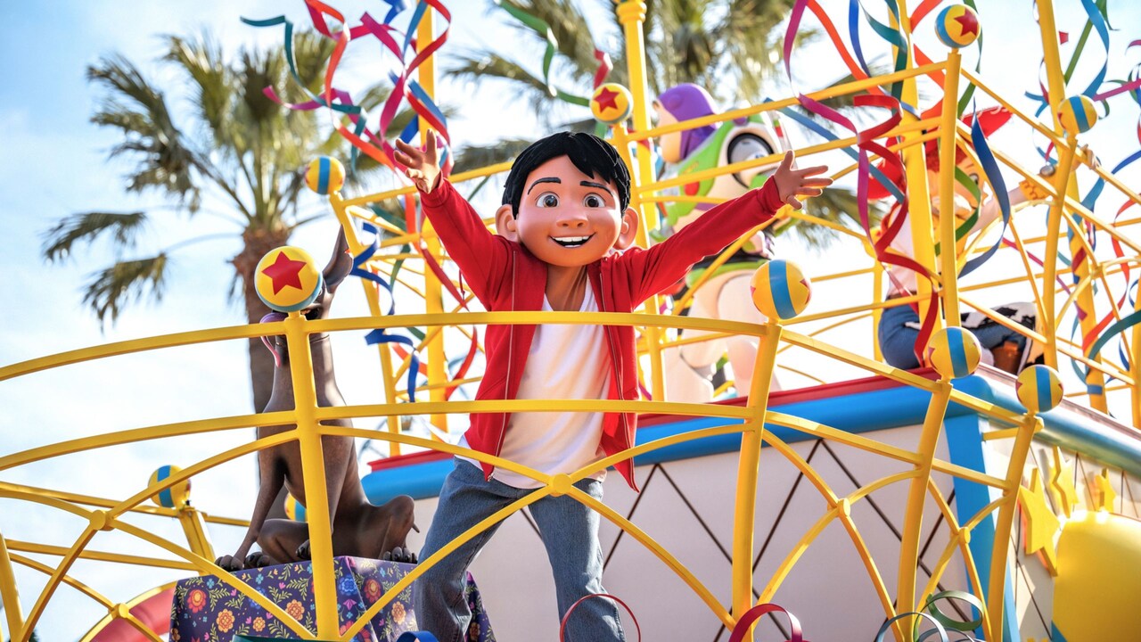 Miguel Rivera standing with his arms outstreched on a Pixar themed float