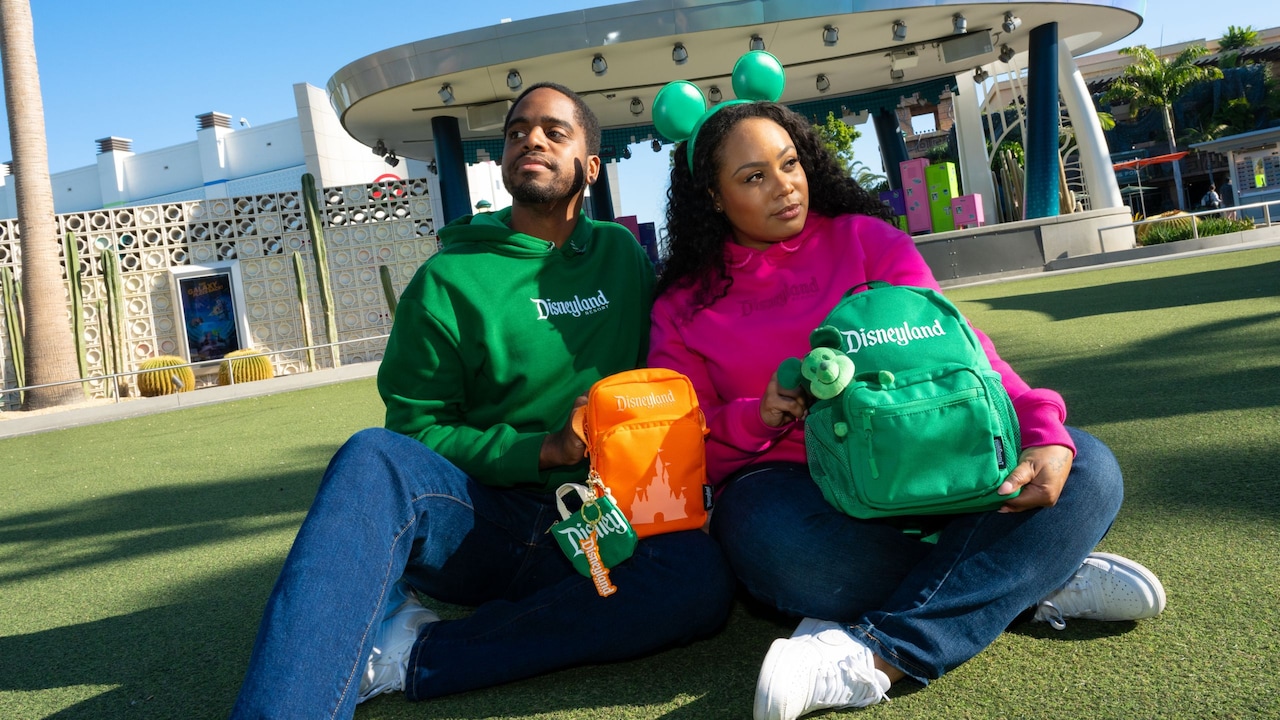 A couple posing with their Logo Mania merchandise collection products in Downtown Disney District