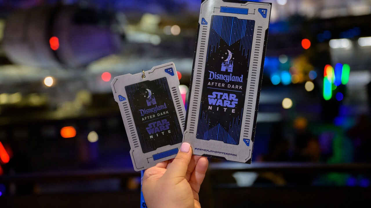 Hands holding a Disneyland After Dark Star Wars Nite credential and guide map in front of Star Wars Galaxy’s Edge in Disney’s Hollywood Studios