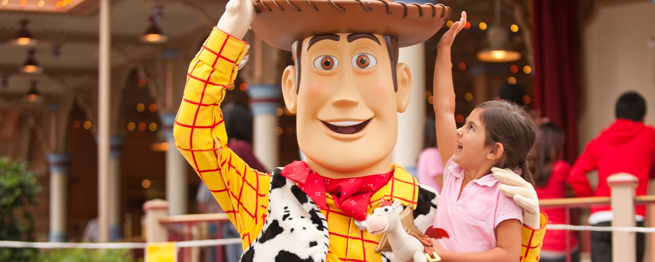 El personaje Woody interactúa con una niña que le toca su sombrero de vaquero y trae un caballo de juguete Bullseye